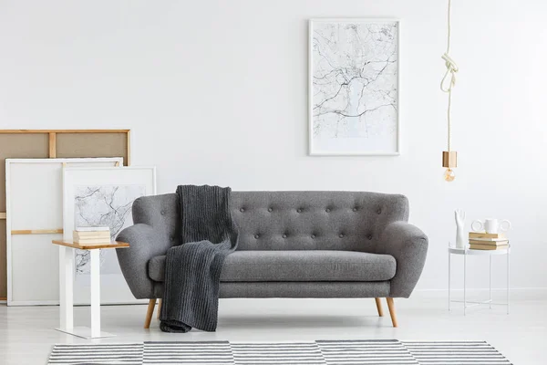 Scandi living room interior with grey, big sofa in the center and modern picture on the wall
