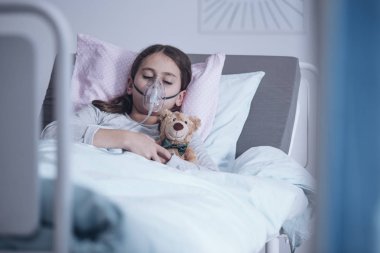 Sick girl with oxygen mask sleeping in a hospital bed with teddy bear clipart