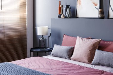 Yakın çekim bir çift kişilik yatak ve yastıklar bir otel odası iç gri duvar, lamba, vazolar ve pencere panjur ile süslenmiş