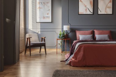 Bir yatak odası iç boya ile zencefil çarşaflı bir köşesinde bir çift kişilik yatak yanındaki koltuk ayakta