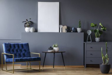 Gri renkli düz ile bitki ve poster mockup iç tablosunun yanındaki Lacivert koltuk