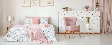 Beyaz Oda iç yeşil bitkiler, taze laleler, basit posterler ve pastel pembe tekli noktalı yatak çift kişilik yatak üzerinde bulundukları
