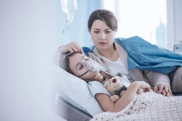 酸素マスクとぬいぐるみと寝て病気の子供を支える心配する母親 — ストック写真