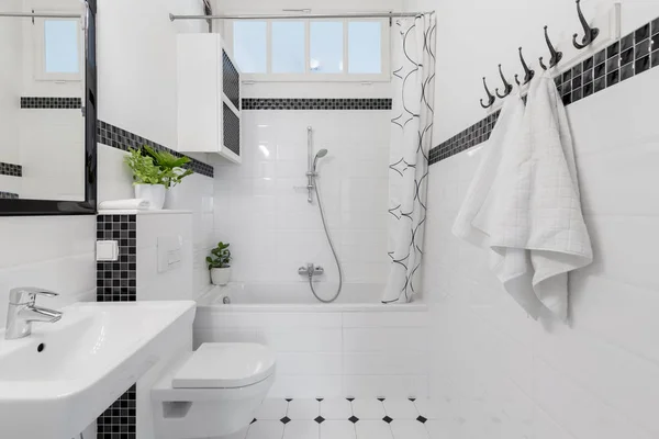 毛巾和镜子在白色和黑色的浴室内部与浴缸和卫生间 真实照片 — 图库照片