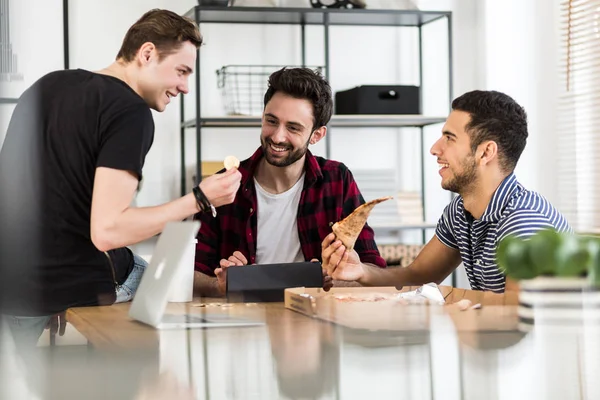 Pizza yemek ve dijital cryptocurrency hakkında konuşurken gülümseyen arkadaşlar