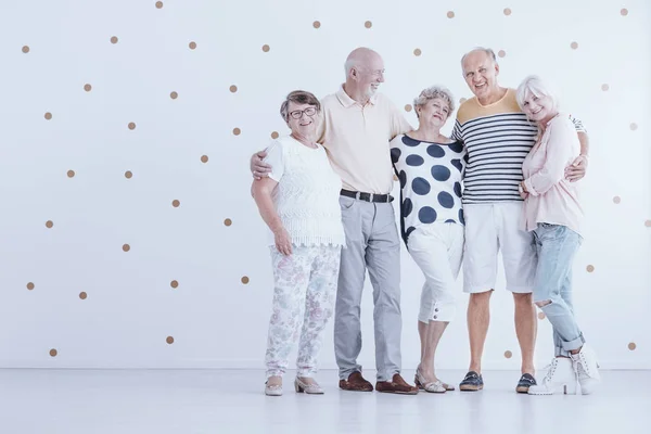 Grupo Amigos Ancianos Abrazándose Estudio Blanco Con Puntos Dorados —  Fotos de Stock