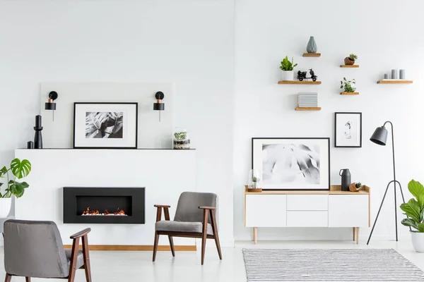 ポスターと暖炉のある白の広々 としたリビング ルームのインテリアの灰色のアームチェア 実際の写真 — ストック写真