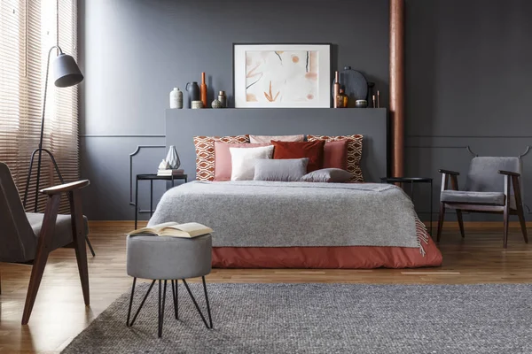 灰色の毛布 ヴィンテージ アームチェア ベッドの上多くの装飾的なクッションと居心地の良い 暗い寝室のインテリアの本物の写真 — ストック写真