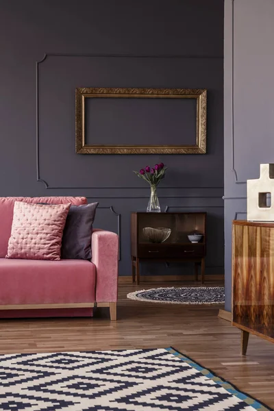 ピンクの装飾的な枕ソファ暗いリビング ルーム インテリア新鮮な花 模様のカーペットとヴィンテージの食器棚に立っています — ストック写真