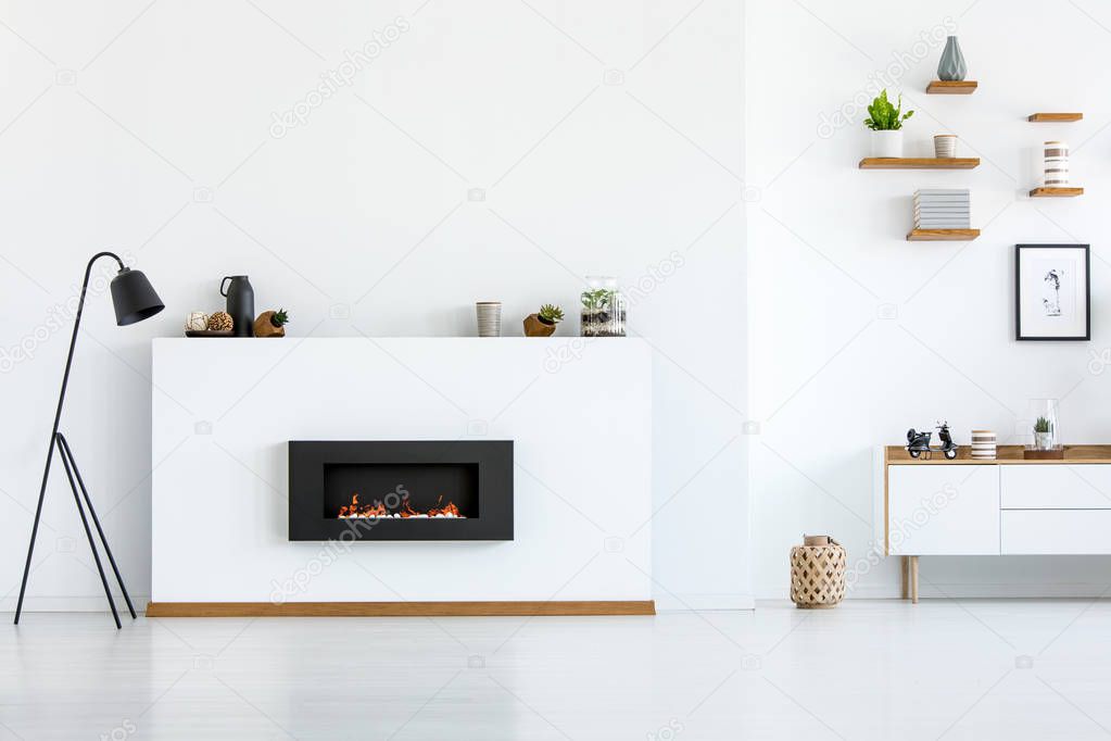 Black lamp next to fireplace in white apartment interior with copy space. Real photo
