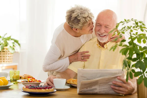 Glimlachend Senior Man Lezing Krant Zijn Vrouw Hem Zoenen — Stockfoto