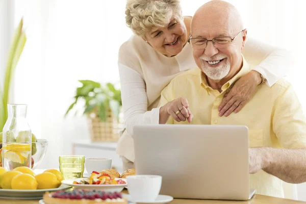 微笑的资深男子使用笔记本电脑与他快乐的妻子 长者使用互联网概念 — 图库照片