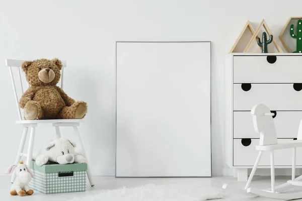 泰迪熊在白色的椅子旁边的白色海报与样机在儿童的房间内部 真正的照片 图形的位置 — 图库照片