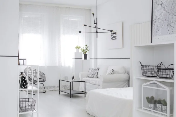 Scandinavian style interior with windows, fresh plants, black metal furniture and modern lamp