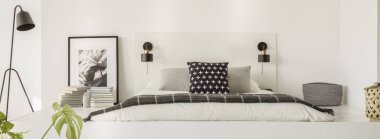 Yatak yastık ve beyaz çarşaflar, kitap, afiş ve küçük sepet platformuyla hazır siyah lamba