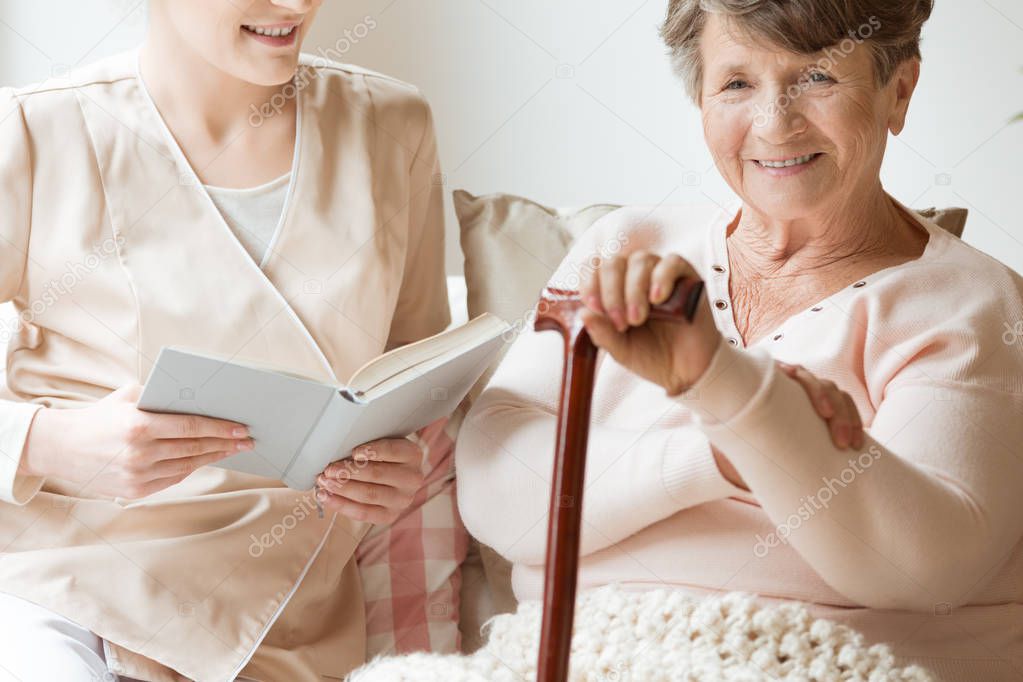 Close-up of smiling senior woman with walking stick and friendly nurse
