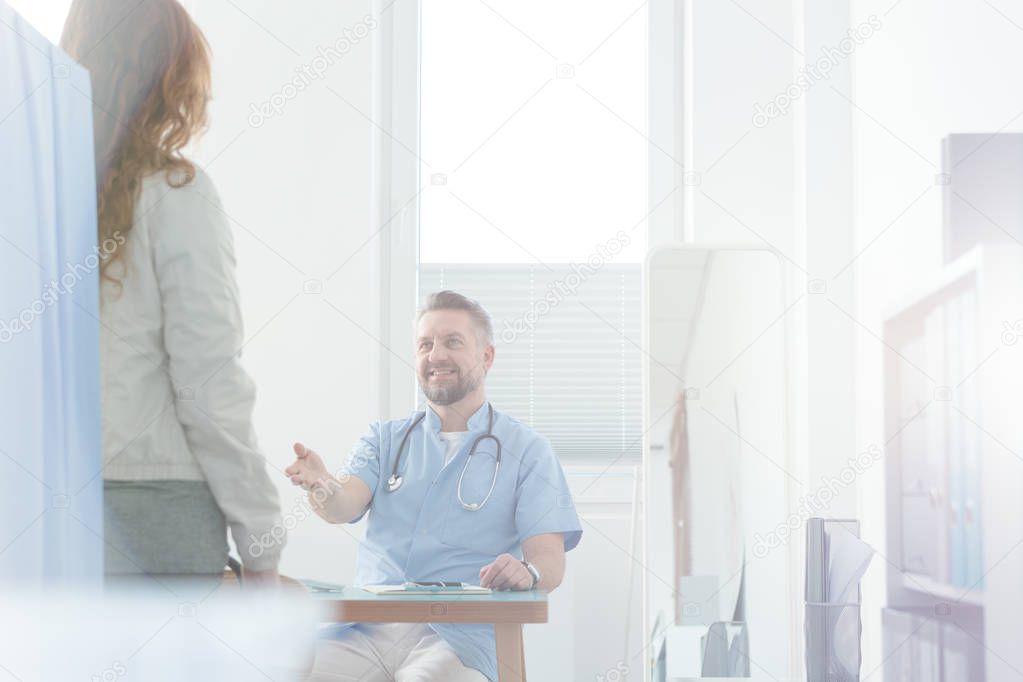 Smiling general practitioner welcoming his patient in the clinic during first appointment