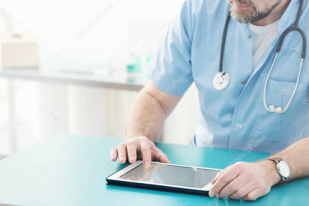 Close-up of doctor with stethoscope using tablet during work
