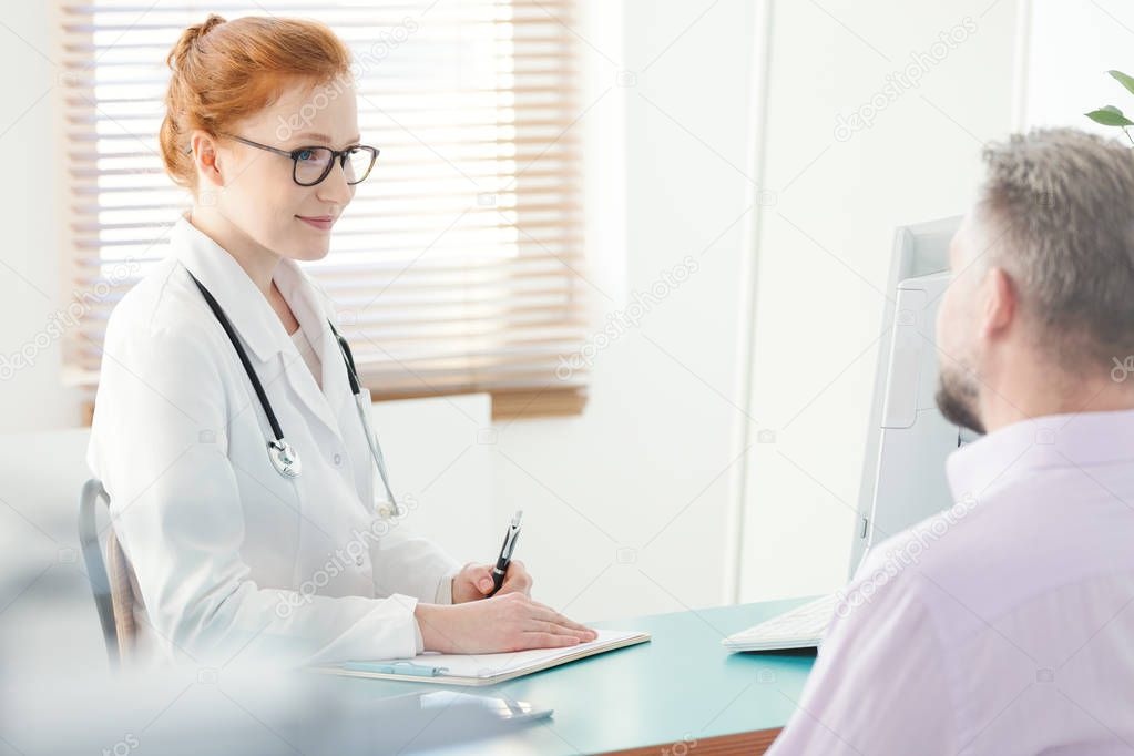 Smiling urologist explaining a problem to a patient in the clinic