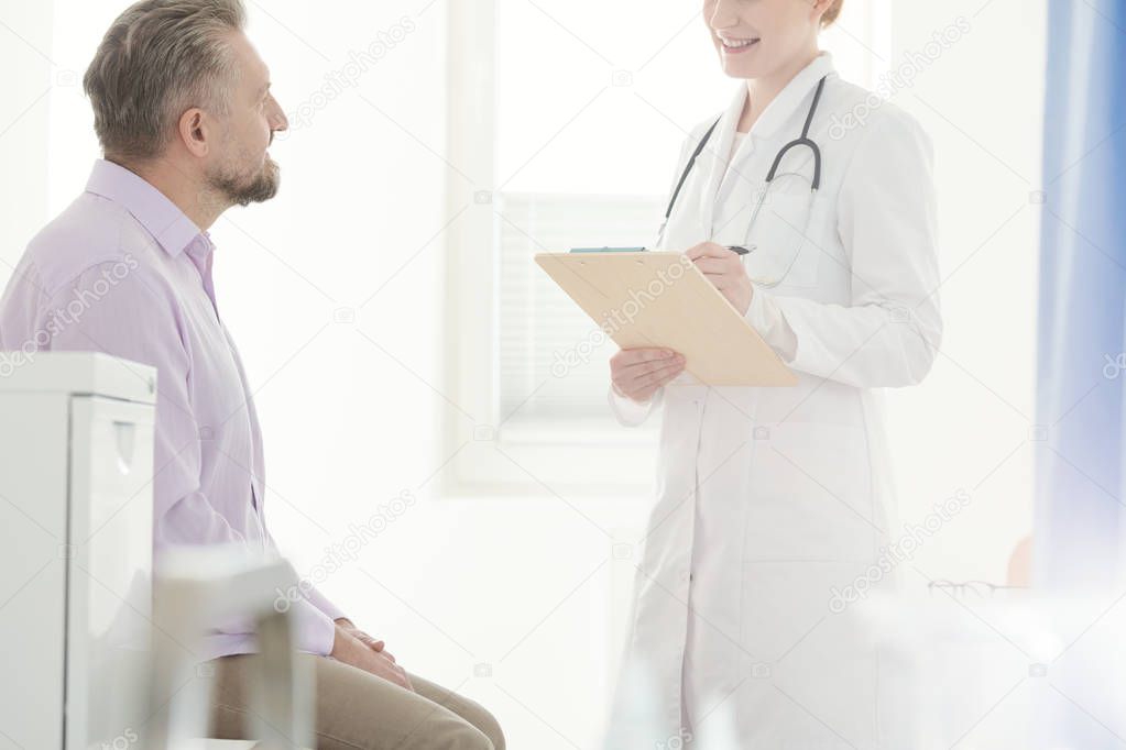 Professional doctor writing a prescription for a sick man in the hospital