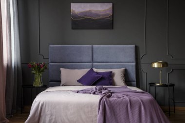 Menekşe otel yatak odası iç çiçek ve kalıplama ile duvardaki resim ile yatakta yanındaki masada altın lamba