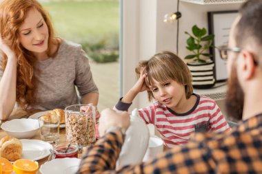 Kahvaltı ailesi ile modern bir oturma odasında bir çocuk