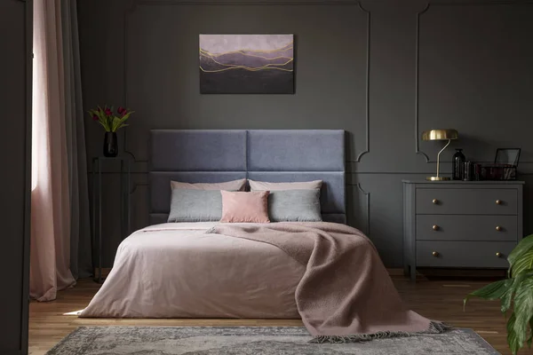 グレーとバイオレットの絵画パステル寝室のインテリアでベッドの横にあるキャビネットの上にゴールド ランプ — ストック写真