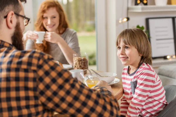 朝は朝食を食べながら彼の父を見て微笑む少年 — ストック写真