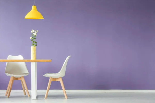 最小的内部有两个白色的椅子 桌子上有一朵花在花瓶里 一盏黄色的吸顶灯对着紫色的墙和复制空间 — 图库照片