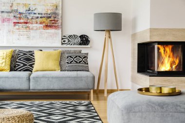 Şömine ve resim ile sıcak düz iç desenli yastıklar kanepeyle arasındaki gri lamba. Gerçek fotoğraf