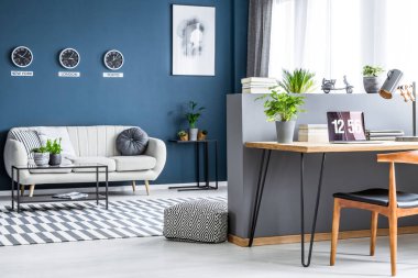 Koyu mavi salon iç üç saatler, basit poster, parlak kanepe ve dizüstü bilgisayar ile ev ofis köşede saç tokası resepsiyon ile