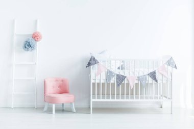 Parlak bebek odası iç ip, pembe koltuk ve ponpon merdivenle üçgenler ile dekore edilmiş bir beşik ile