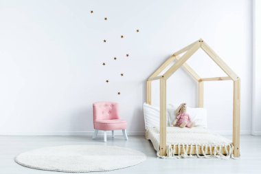 Pembe sandalye beyaz duvar çıkartmaları basit çocuk yatak odası iç ahşap oda ile karşı. Gerçek fotoğraf