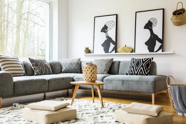 坐垫凳产品在明亮的非洲起居室的地毯上 里面有灰色的角落沙发和海报 真实照片 — 图库照片