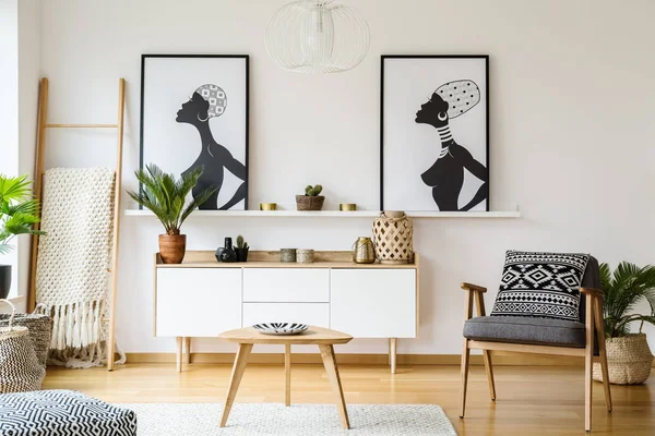 Sessel Neben Holztisch Hellen Wohnzimmerinterieur Mit Postern Über Dem Schrank — Stockfoto