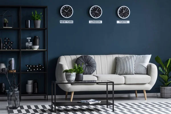 Schwarzer Tisch Neben Beigem Sofa Gegen Marineblaue Wand Mit Uhren — Stockfoto