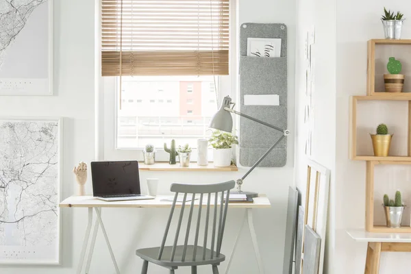 一张办公桌的前视图 笔记本电脑和台灯站在窗口 墙壁组织者和架子与仙人掌在家庭办公室内 — 图库照片