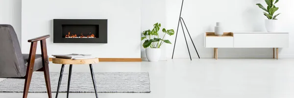 Weißes Wohnzimmer Mit Kamin Beistelltisch Mit Zeitschriften Neben Grauem Sessel — Stockfoto