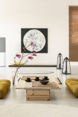 Bir resim, bardak ve yerde sarı yastık ile sehpa ile Japon oturma odası iç kiraz çiçeği