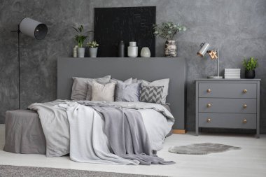 Yaprak yatak dolabı ve lamba gri yatak odası iç siyah posteri ile arasında. Gerçek fotoğraf