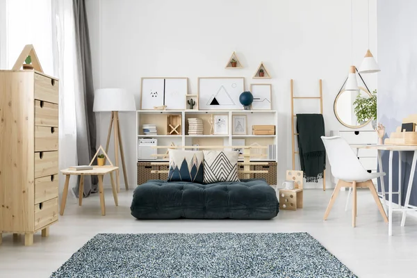 绿色折叠床垫和图案放置在斯堪的纳维亚客厅内部与木制家具和简单的画廊 — 图库照片