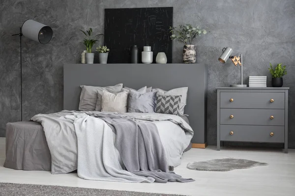 Yaprak yatak dolabı ve lamba gri yatak odası iç siyah posteri ile arasında. Gerçek fotoğraf