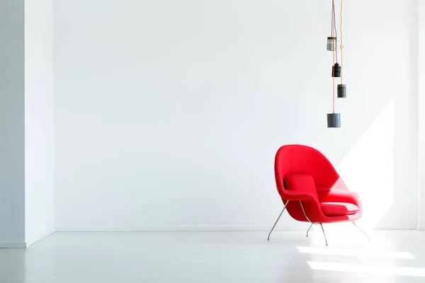 ランプの下で赤い肘掛け椅子と最小限のリビング ルームのインテリアの白い空の壁上の領域をコピーします 実際の写真 — ストック写真