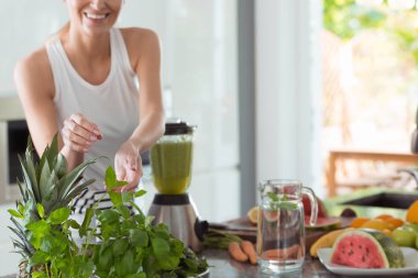 Uygun kadın onun sağlıklı kokteyl için taze nane yaprağı toplamak