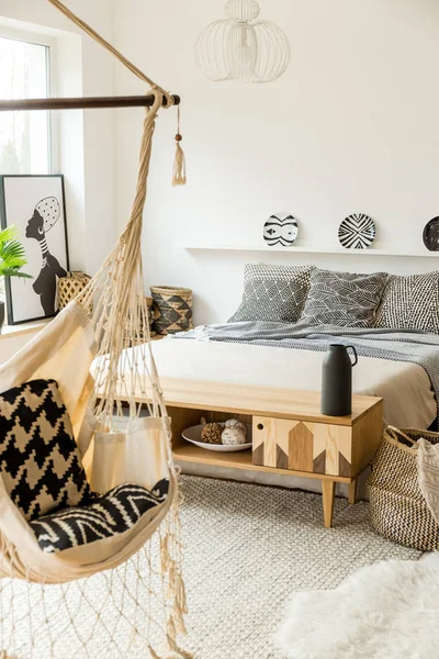 Önünde parlak yatak odası iç desenli tabak ve hamak ile yatakta ahşap rustik dolap