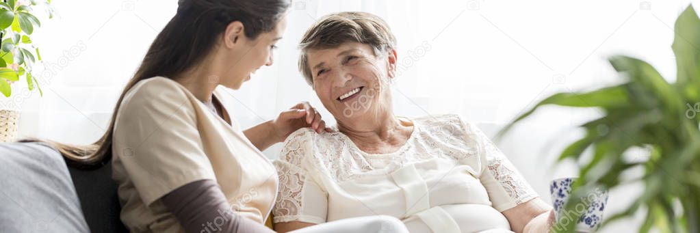 A caregiver and caretaker sitting and chatting in a nursing home