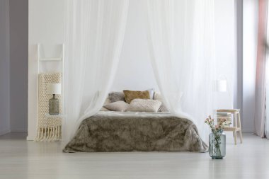 Cam vazo ayakta beyaz yatak odası iç katta merdiven üzerinde battaniye, lamba başucundaki ve kürk yorgan ve yastıklar ile kral yatak ile taze çiçekler