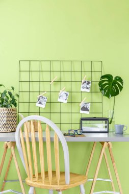 Polaroid fotoğraf ile metal Organizatör gözlüklerle defter ve grey çay Kupası ayakta yeşil oda iç çalışma köşe masanın üzerine yerleştirilen
