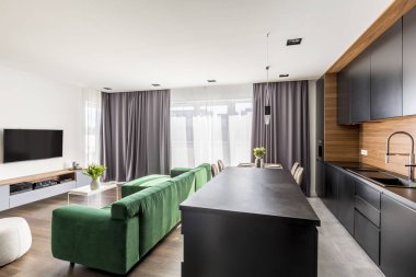 Otel odası iç yeşil salonu, Tv seti, windows perdeler ve açık alan mutfak köşesi ile gerçek fotoğraf