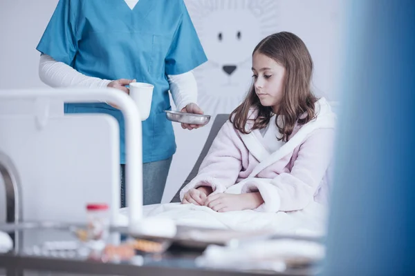 护士给生病的女孩在医院的药丸和茶 — 图库照片